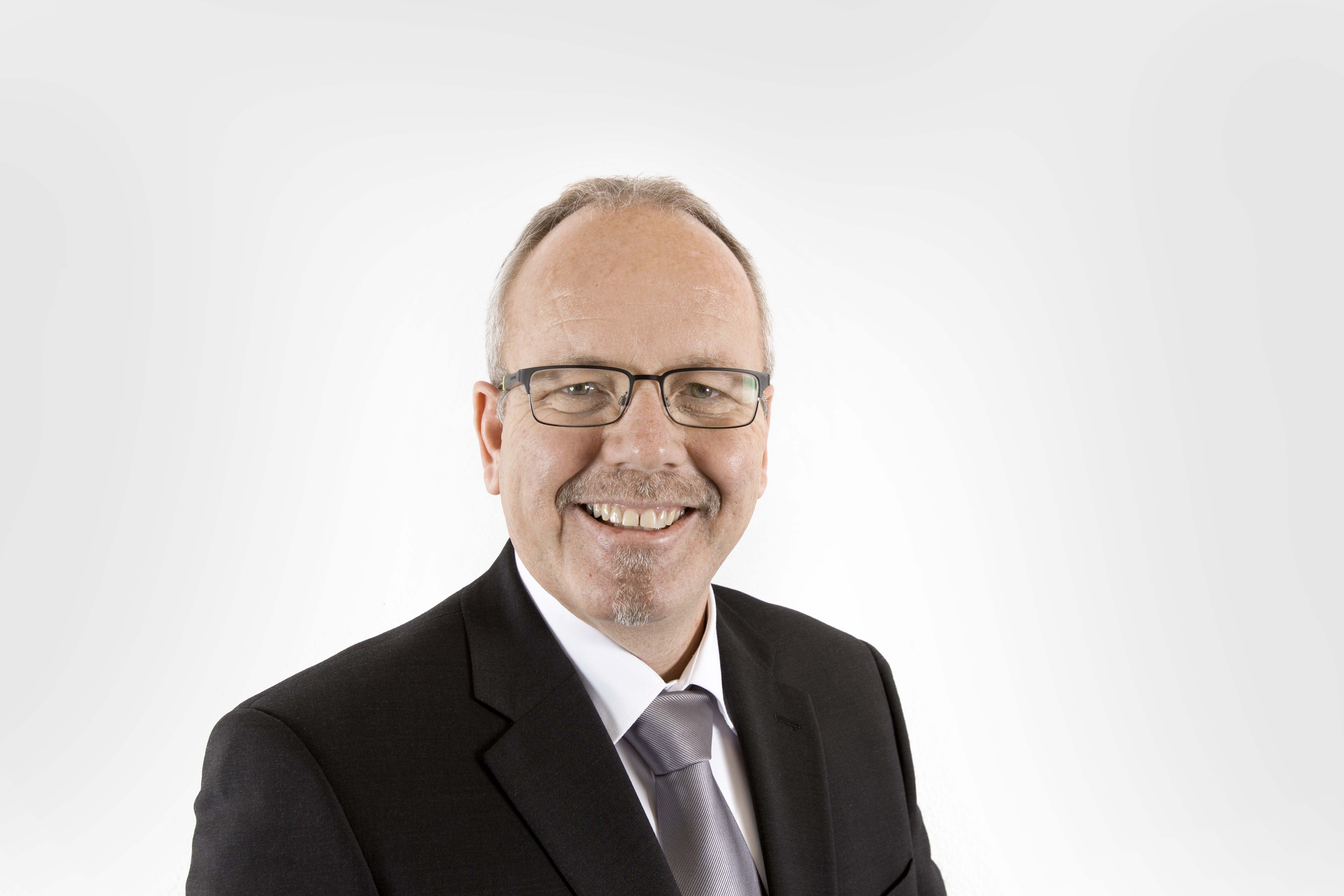Tomas Fleischmann Vertrieb Gastronomie, Portrait mit Anzug, trägt eine Brille. Der Hintergrund ist hell.